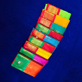 Top view of multiple amman saree big kota folded in assorted bright colors with gold zari border on blue surface
