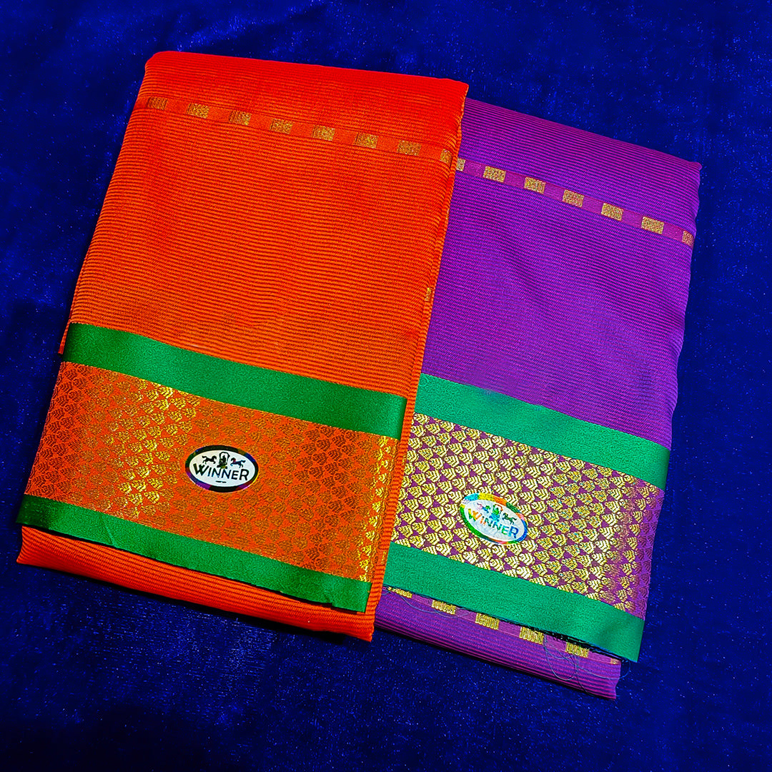 Two folded Amman sarees in Red and Violet with green and gold zari border placed flat on a blue velvet surface.