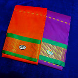 Two folded Amman sarees in Red and Violet with green and gold zari border placed flat on a blue velvet surface.