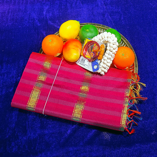 Slight top angle view of pink amman saree multicolour checked with gold stripe in a gold plate with fruits on blue surface
