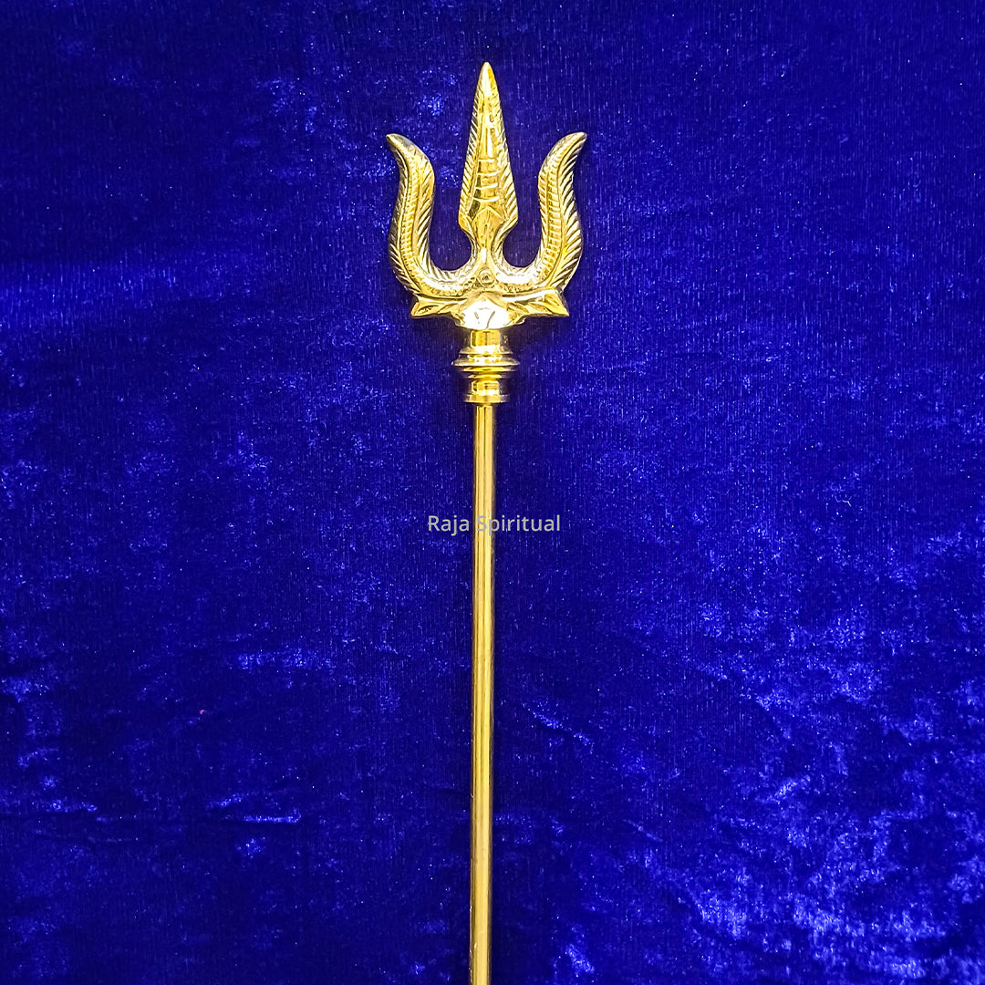 Brass muppattai sulam trishul 3.5ft with feather-edged trident head shown in straight upright front view against blue velvet backdrop.