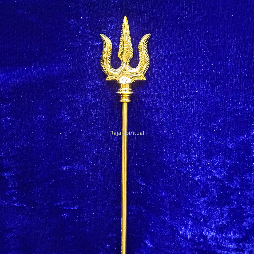 Brass muppattai sulam trishul 4ft with curved horn-edged trident head shown in straight upright front view against blue velvet backdrop.