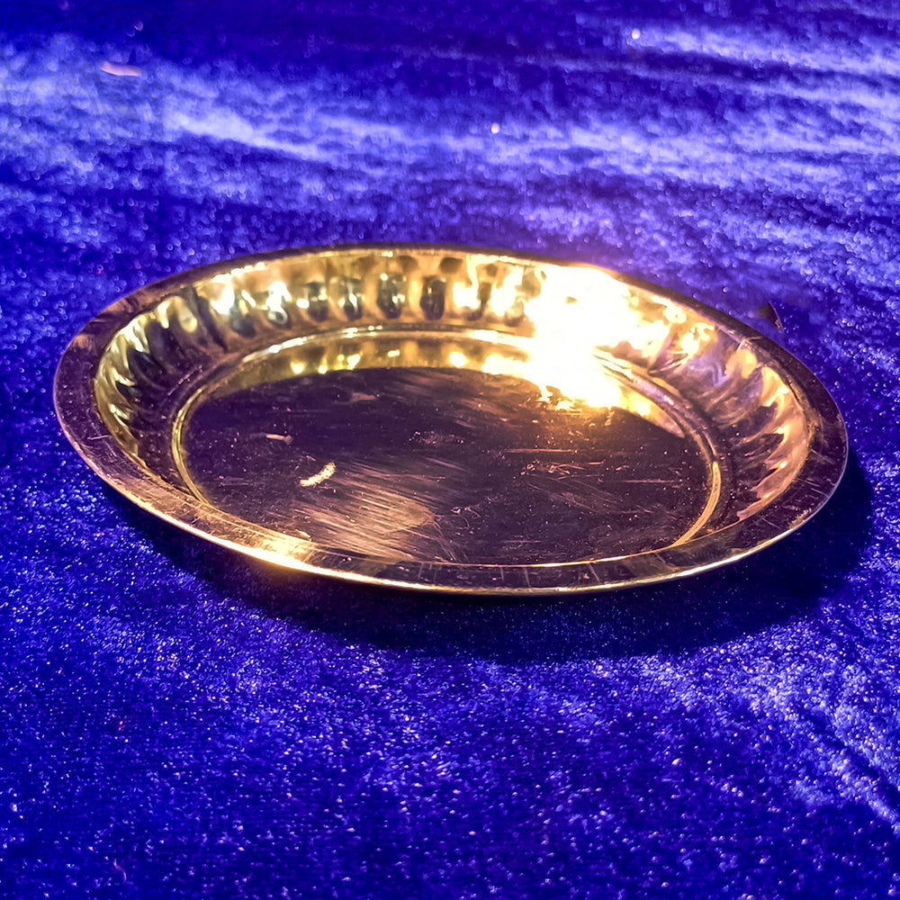Brass sargam plate with ridged rim, empty pooja plate, side angle view on blue velvet background
