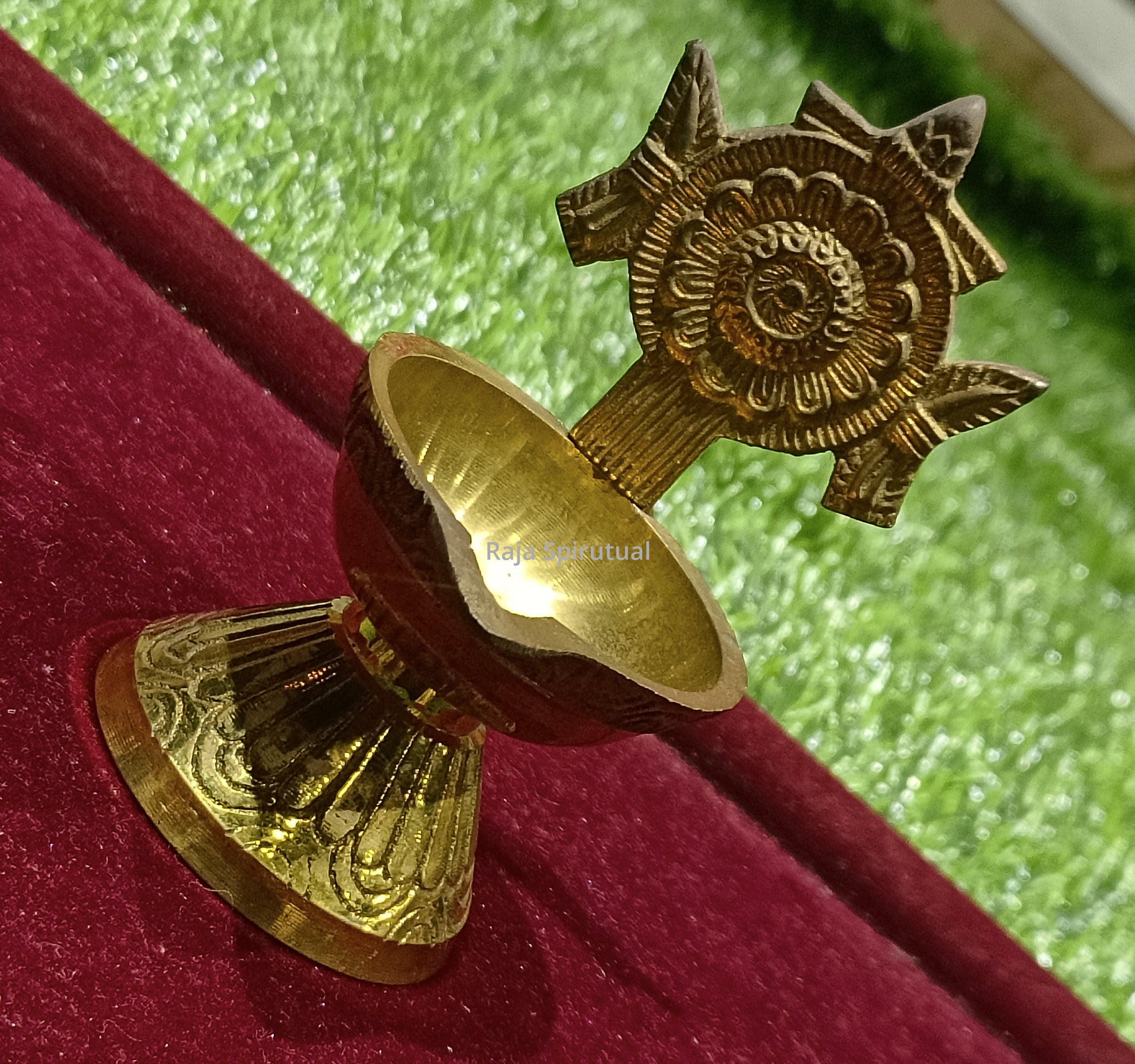 Fancy chakaram vilaku top right diagonal view detached oil cup engraved base and chakaram disc on red velvet green background
