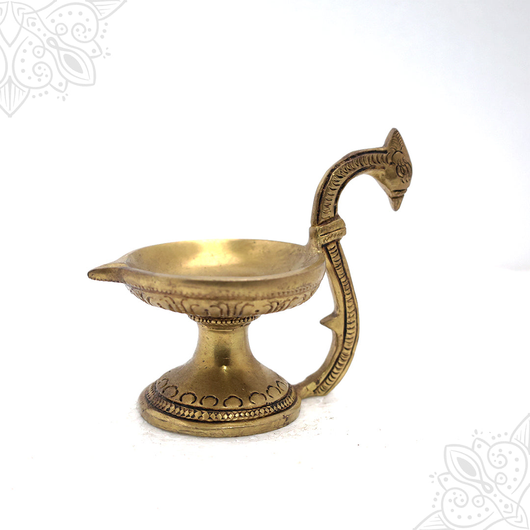 Fancy cup Vilakku with peacock head handle and engraved base in a slight left-angle view against a white backdrop