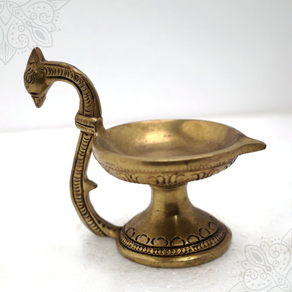 Fancy cup vilaku with peacock handle in a slight right side angle view on a white background
