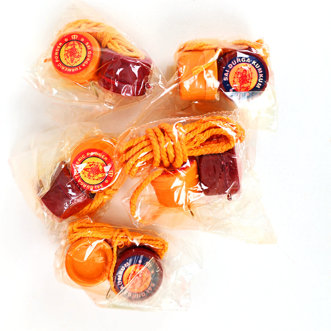 Five Sai Durga thali saradu combo sets in clear plastic packs with turmeric kumkum boxes and yellow thread in top-down view against white backdrop.
