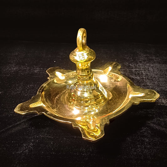 Thongu vilaku weight slight low right angle with glowing lit wicks on wavy oil tray and ring hook against dark black background